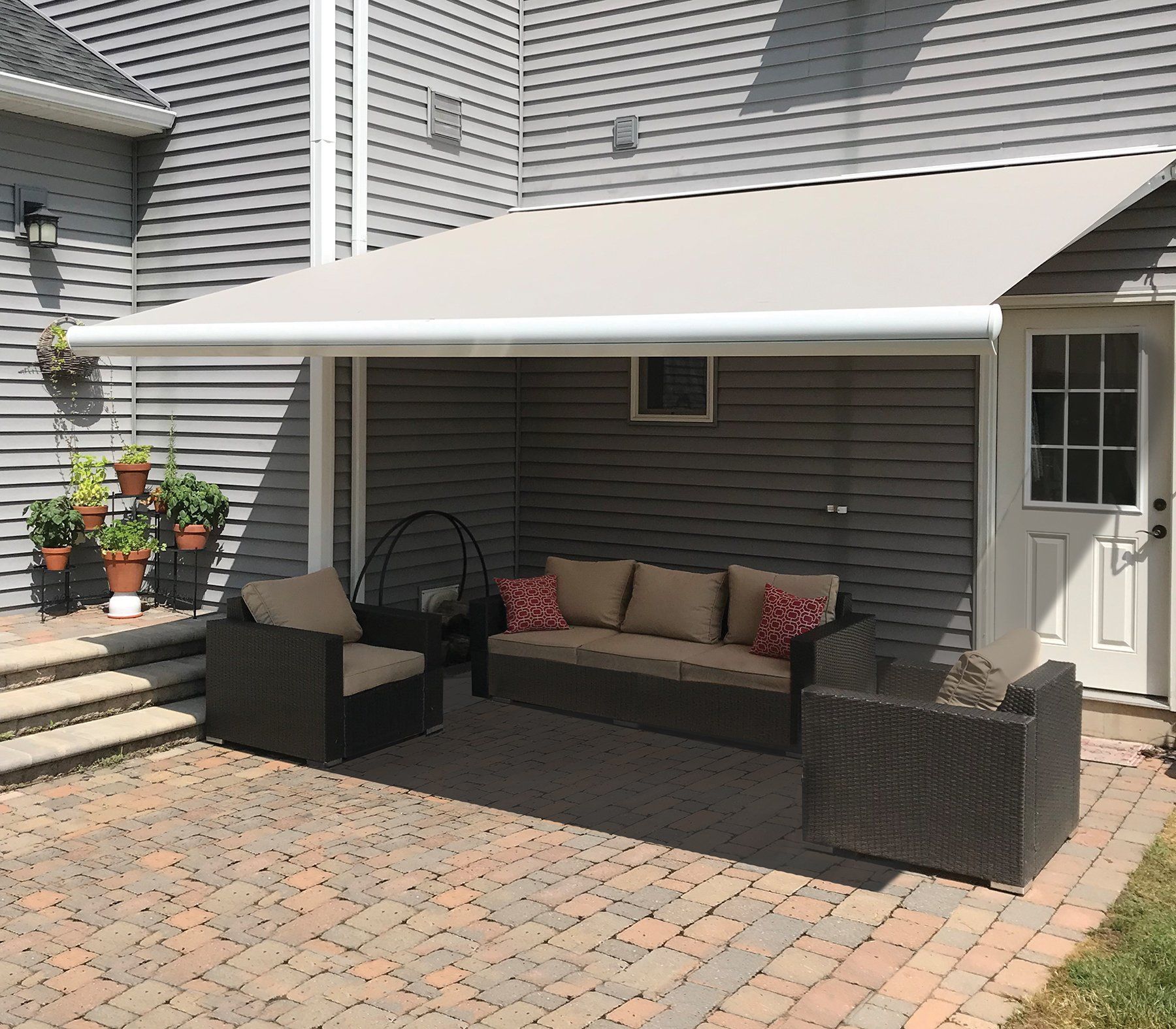 A patio with a couch and chairs under an awning