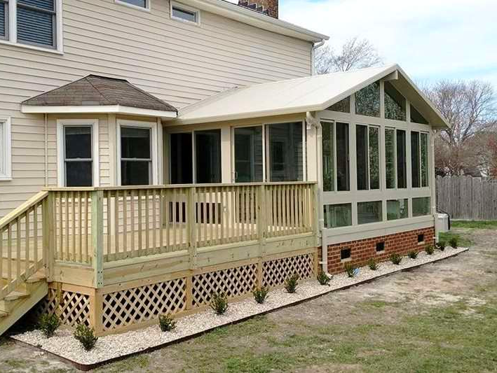 A house with a screened in porch and a wooden deck.