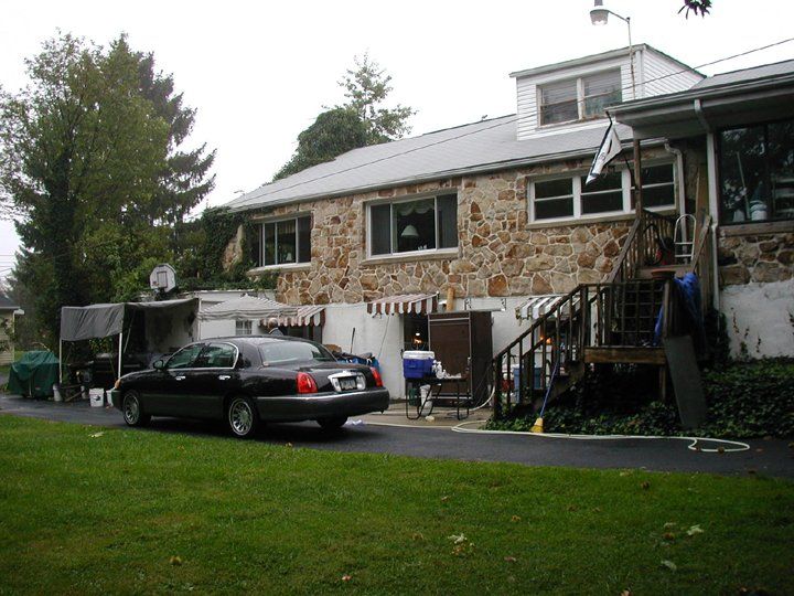 A black car is parked in front of a stone house
