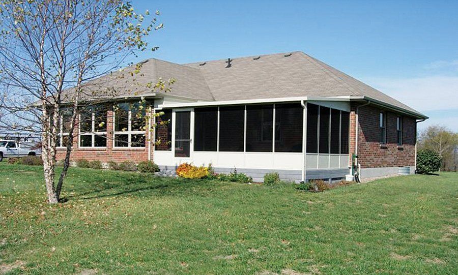 GO TO SCREEN ROOMS a brick house with a screened in porch in the backyard .