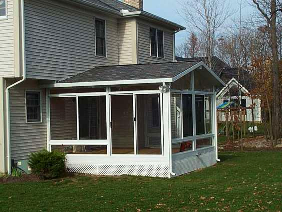 A screened in porch in the backyard of a house