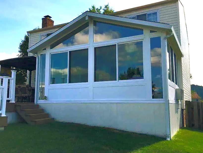 A white house with a sunroom on the side of it