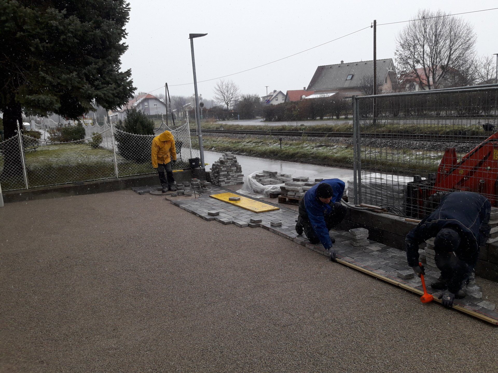 Arbeiter reparieren an einem regnerischen Tag einen Uferweg neben einem Kanal.