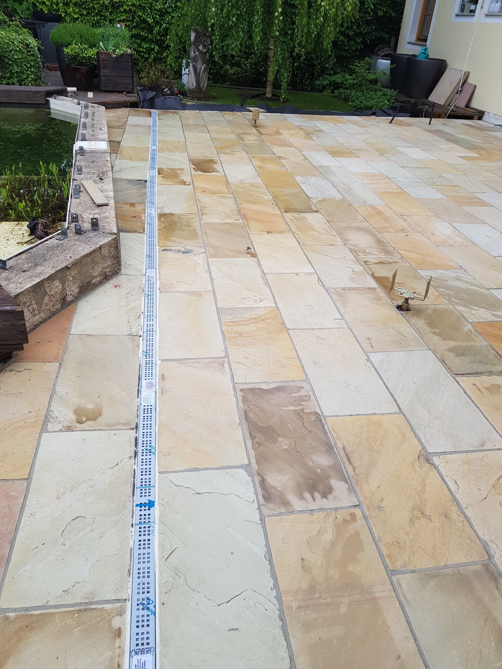 Terrassenplatten mit einem Maßband, das entlang der linken Kante angelegt ist.