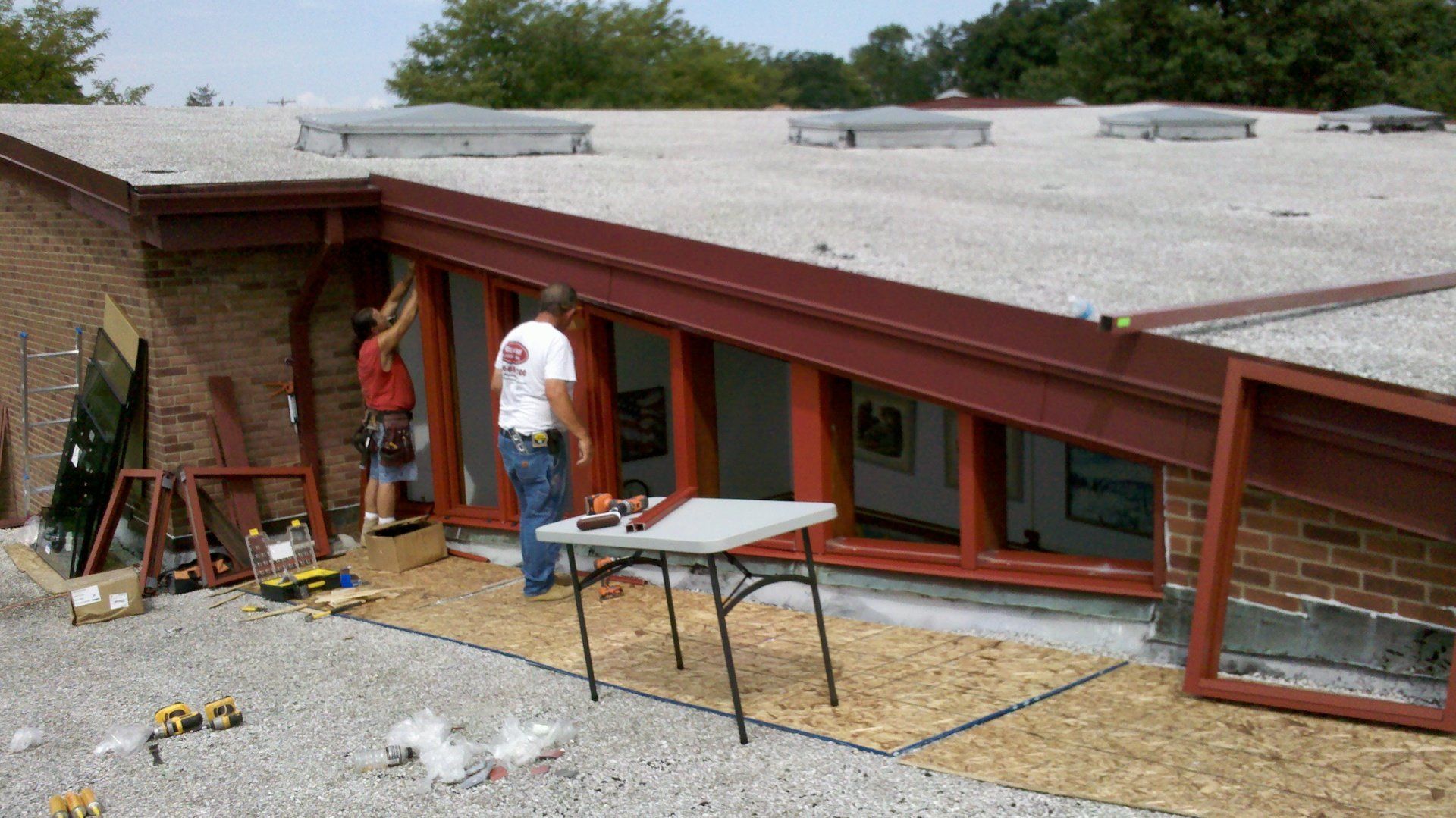 A man is standing in front of a brick building with a table in front of him.