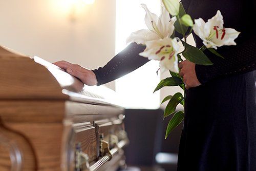 Donna con fiore che accarezza una bara