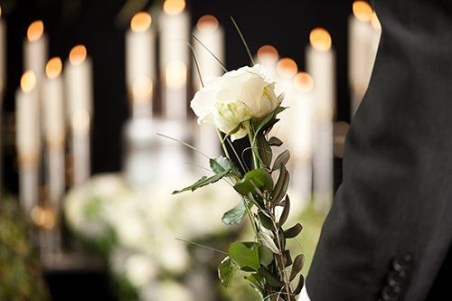 Uomo che regge una rosa con candele accese in sottofondo