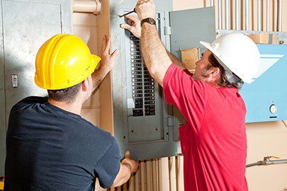 Electricians working together to repair an industrial circuit panel
