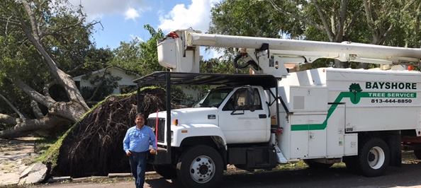 A man is standing next to a white truck with a crane on top of it.