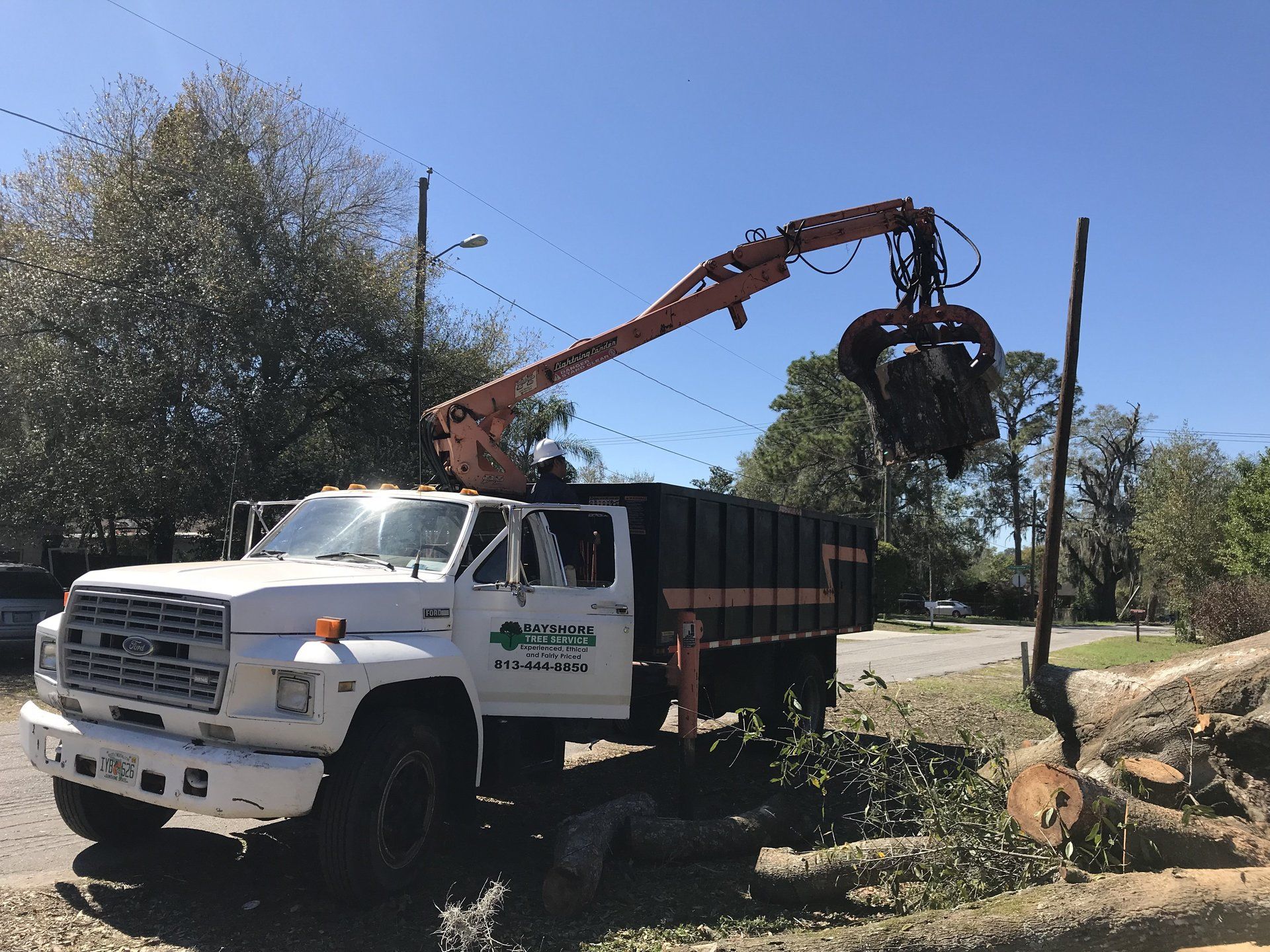 A white truck with a crane attached to the back of it.