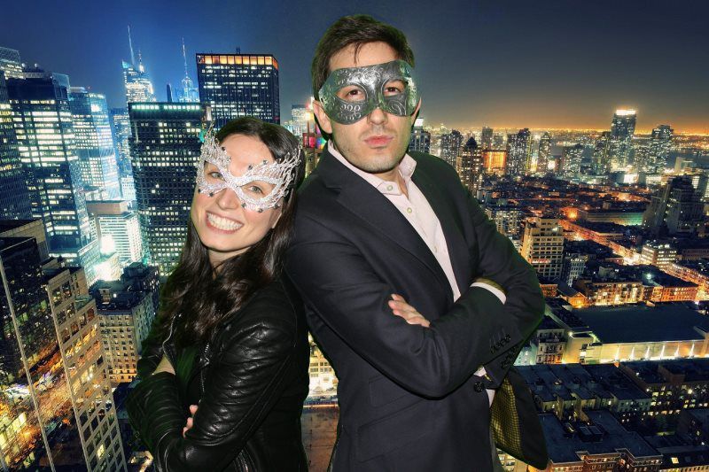 A man and a woman wearing masks are posing for a picture in front of a city skyline.