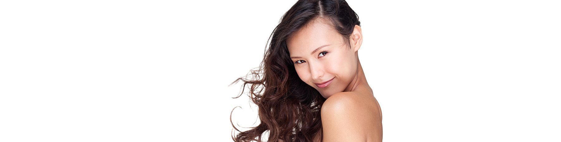 Woman with long, wavy brown hair, looking over her shoulder, bare shoulder, white background.