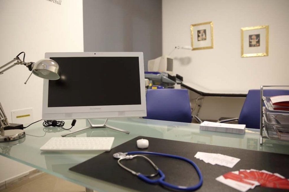 una scrivania con un monitor, tastiera,mouse e uno stetoscopio