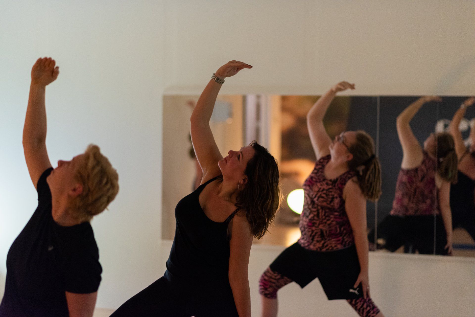Een groep vrouwen doet yoga voor een spiegel.