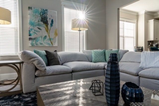 Bright living room with light gray sectional sofa, art, and sunny window.