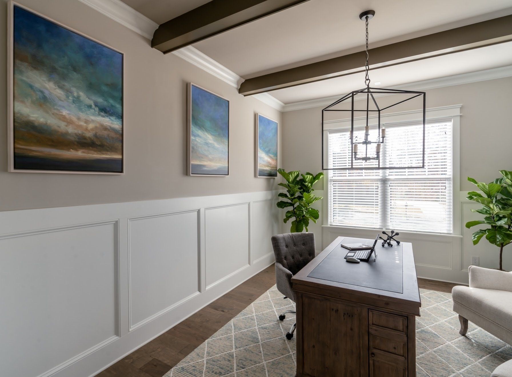 Office with desk, artwork, and plants, featuring wood paneling and a neutral color scheme.