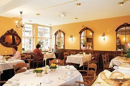 Menschen sitzen an Tischen in einem Restaurant mit gelben Wänden