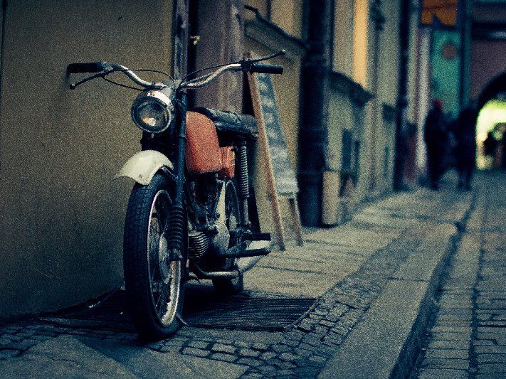 Am Rand einer Kopfsteinpflasterstraße ist ein Motorrad geparkt.