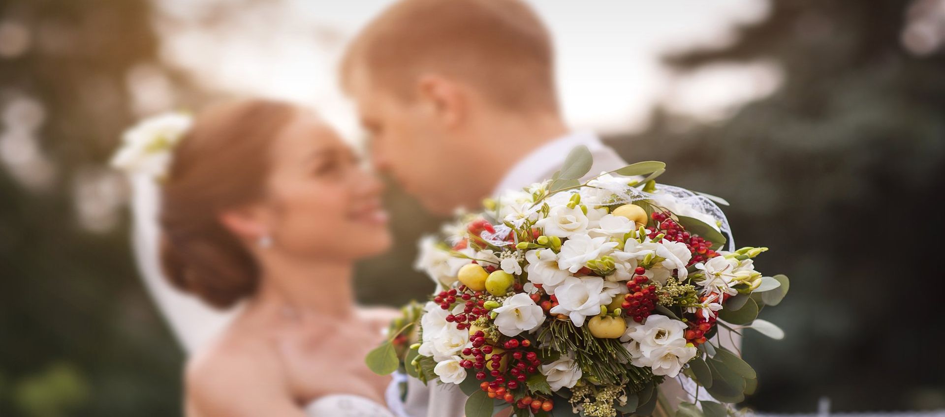 Eine Braut und ein Bräutigam küssen sich, während die Braut einen Blumenstrauß hält.