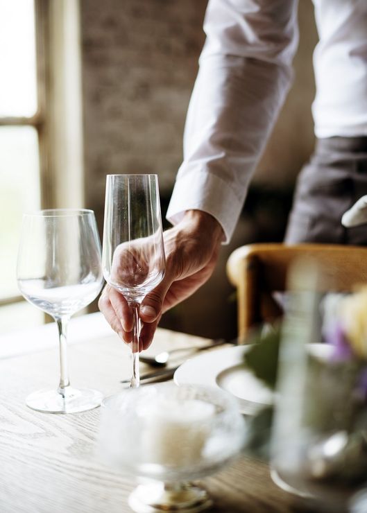 mano di un uomo che prende un bicchiere dalla tavola del ristorante