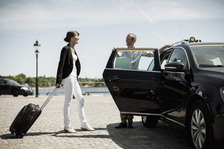 lady walking with a trolley and using an executive taxi service