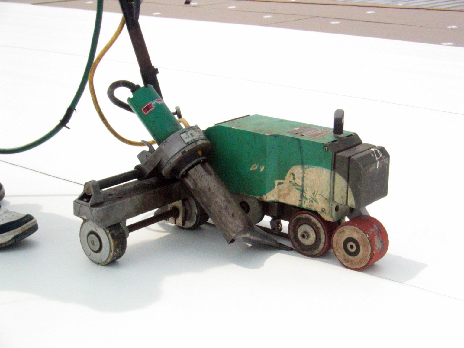 a green machine with wheels sitting on a white surface