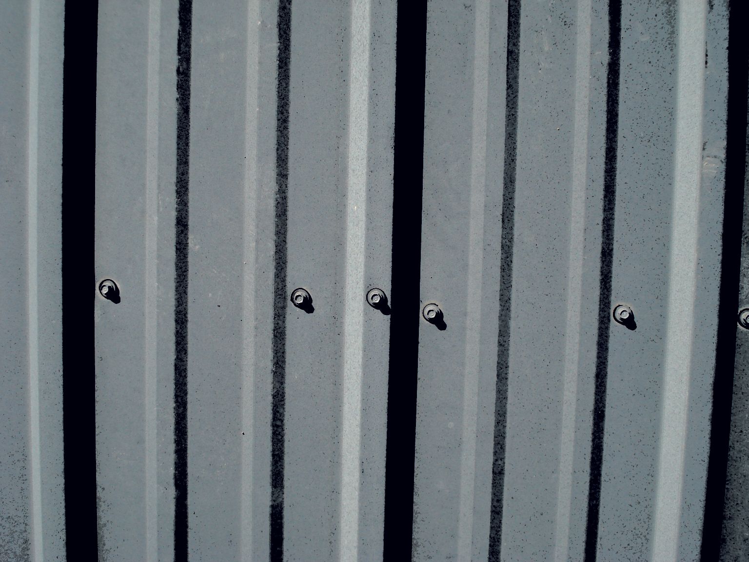 a close up of a gray metal roof with screws on it .