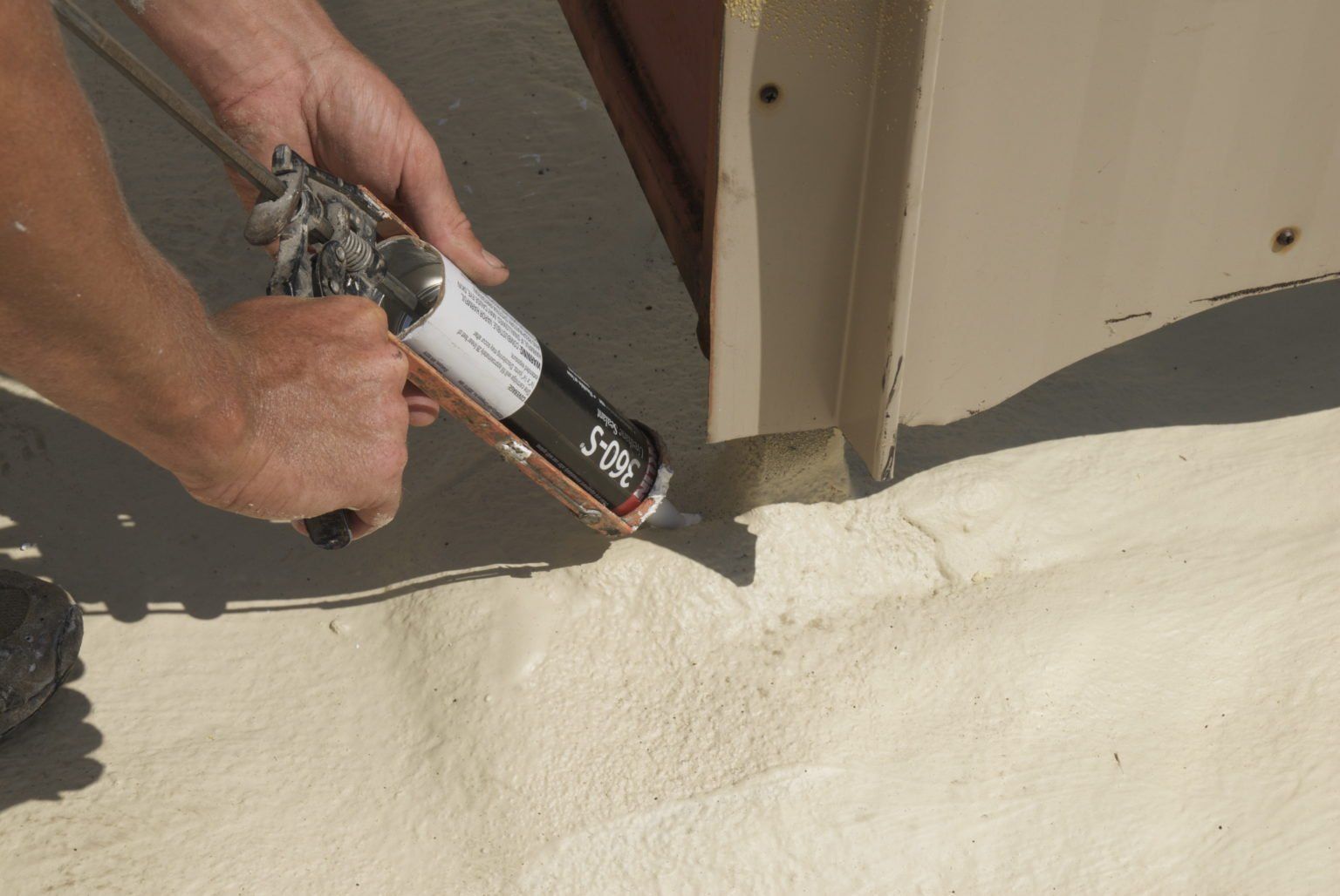 a person spraying roofing insulation on a surface
