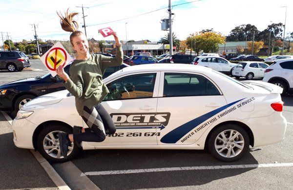 girl jumping next to car with new license