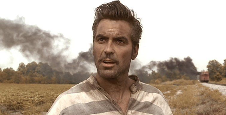 A man in a striped shirt is standing in a field.