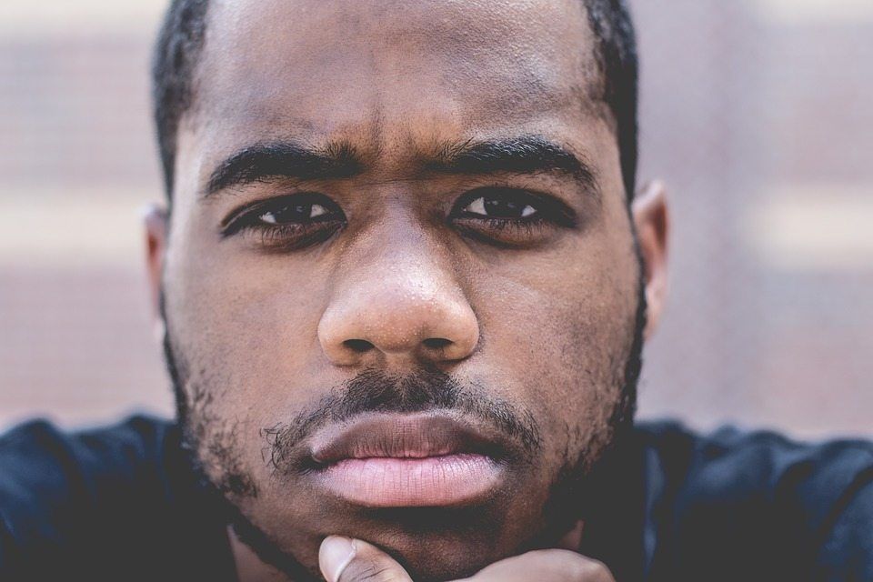 A close up of a man 's face with his hand on his chin.