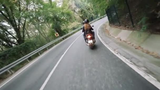 A person is riding a motorcycle down a curvy road.