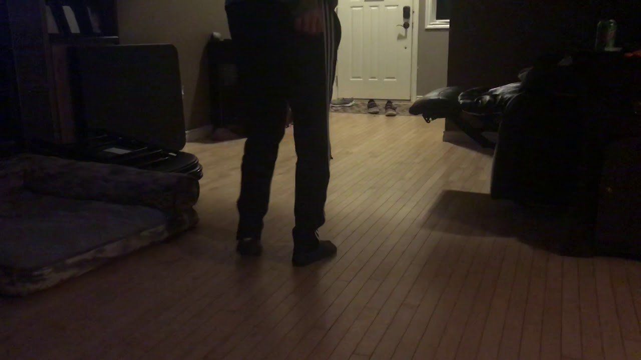 A person is standing in a dark room with a wooden floor.