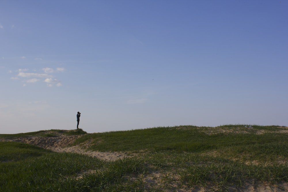 A person is standing on top of a grassy hill.