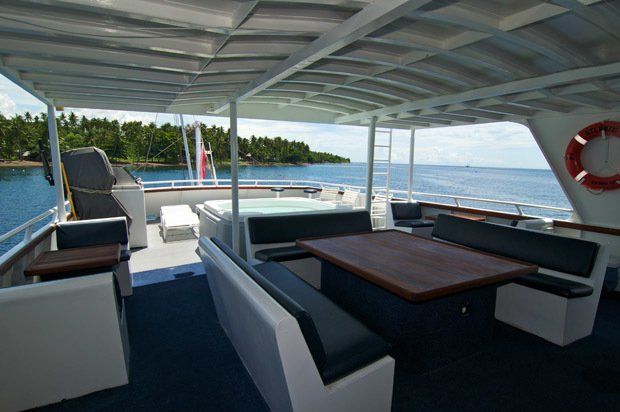 Boat deck with hot tub, seating, and ocean view.