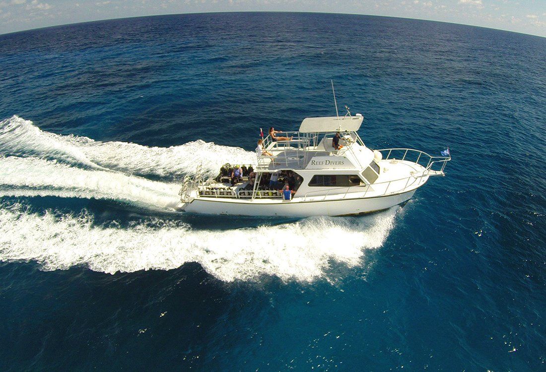 White boat speeding across blue ocean, creating a white wake.