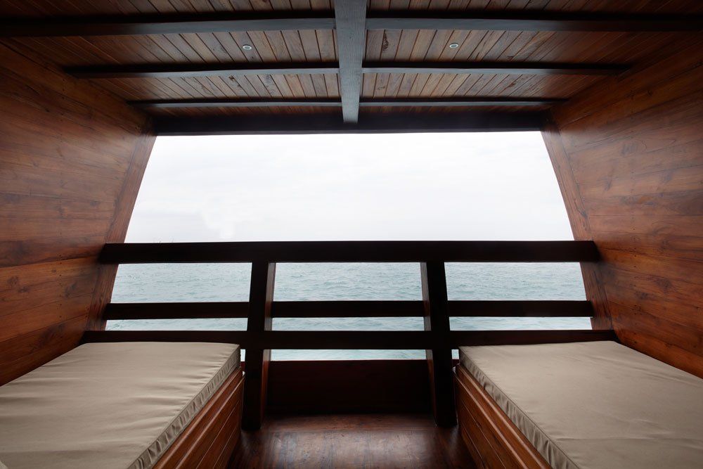Interior of wooden boat cabin with two beds, overlooking water.