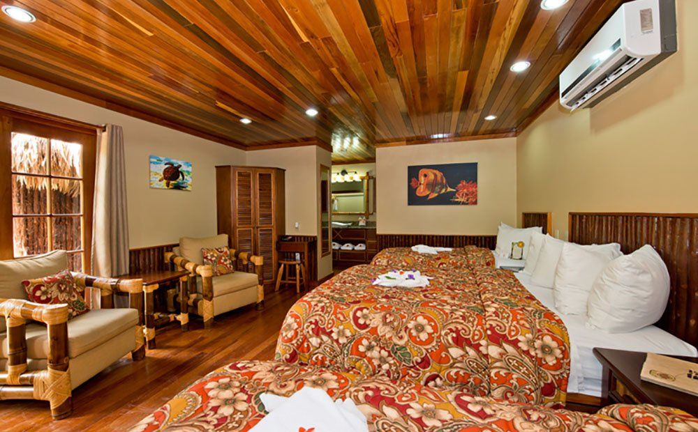 Hotel room with two beds, wood paneling, and seating area.