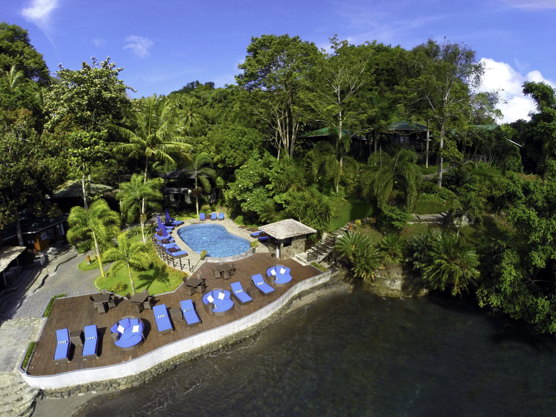 Aerial view of a tropical resort: pool, beach, lush greenery, and