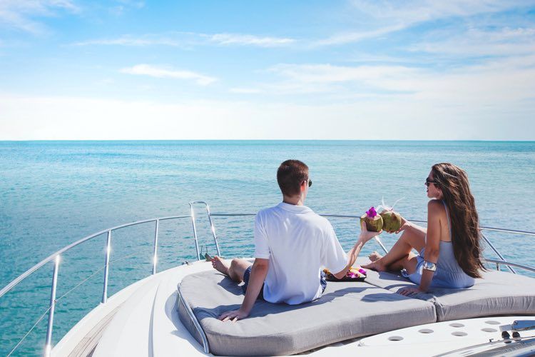 Couple relaxing on a yacht, enjoying drinks and ocean views.