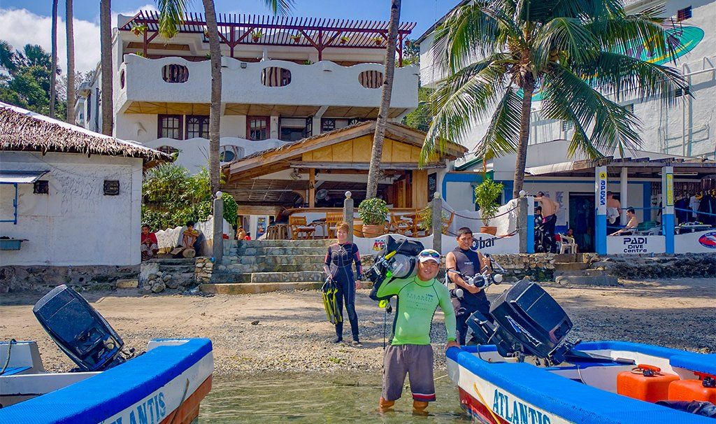 Boats on the water near a waterfront building with people preparing for diving.