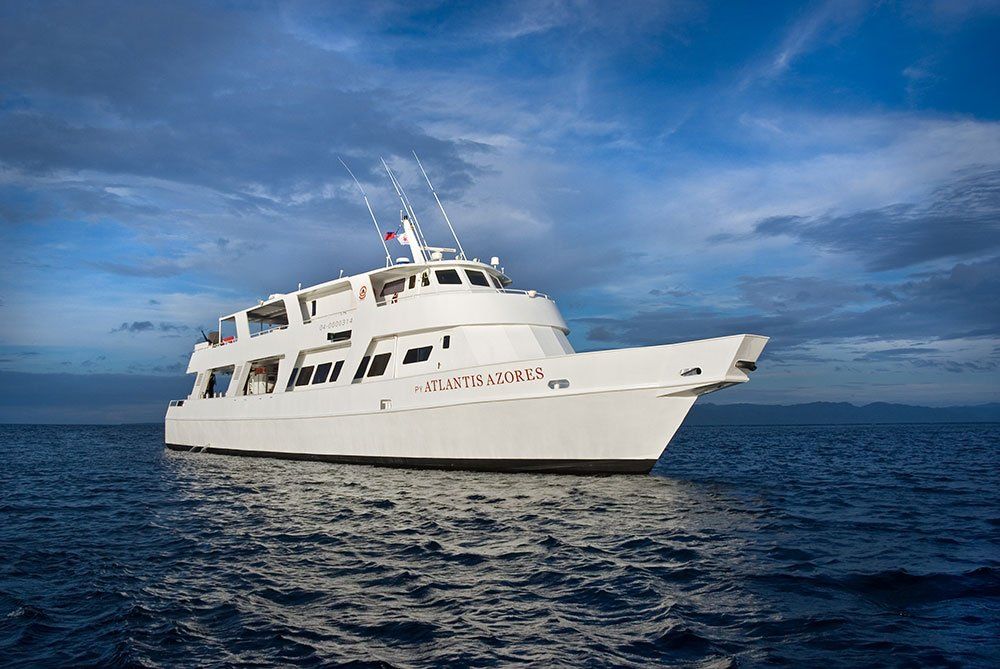 White boat floating on calm ocean under a partly cloudy sky.