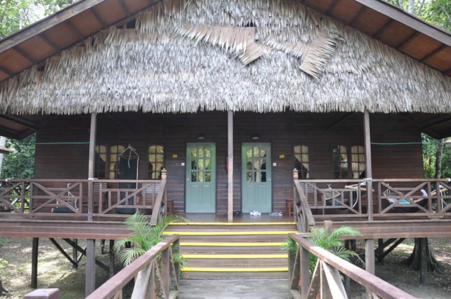 Wooden lodge with thatched roof and elevated wooden deck.