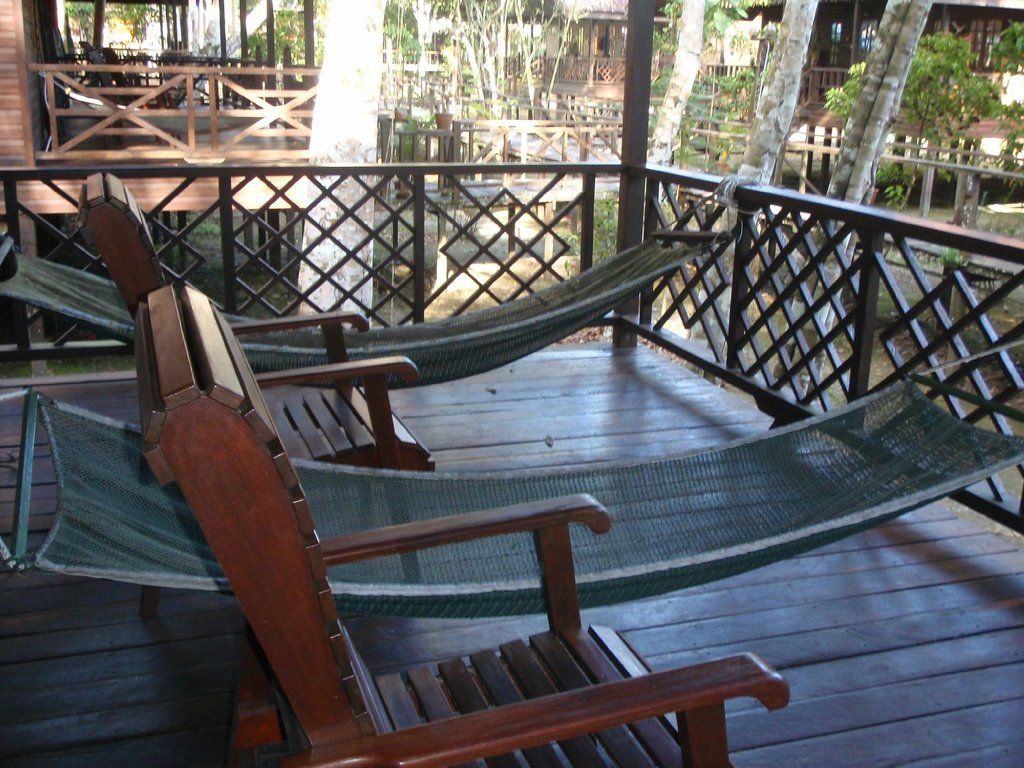 Wooden deck with two hammocks and two wooden chairs.