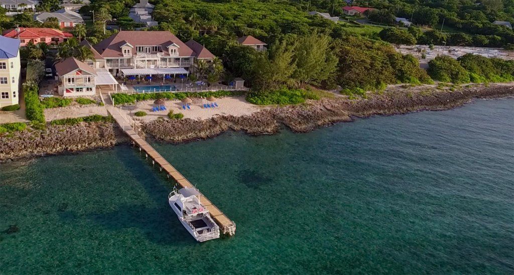 Oceanfront resort with pier and boat; blue water and rocky shoreline.