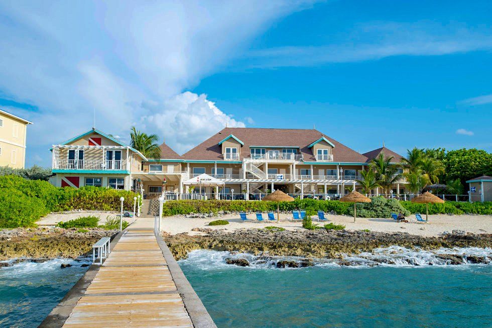 Beachfront resort with pier, light blue ocean, and clear sky.