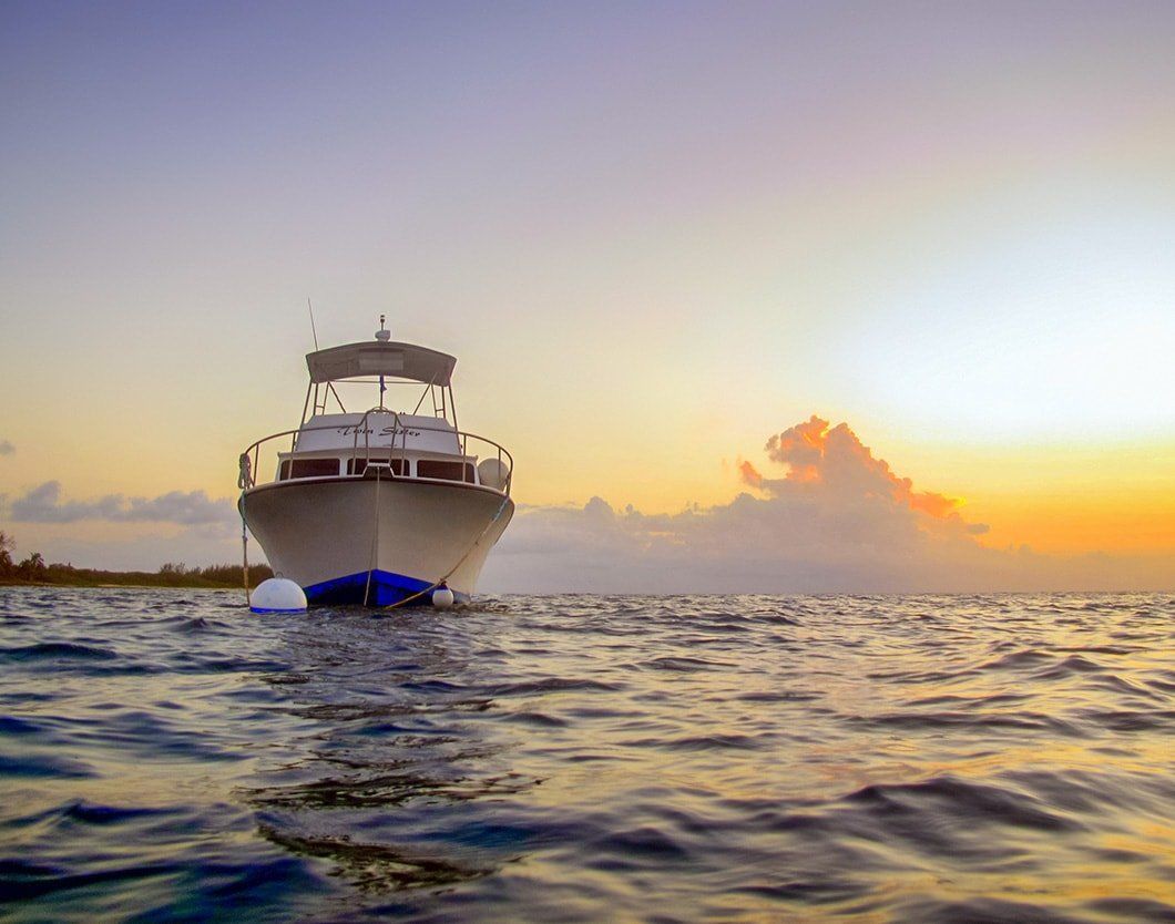 Boat floating on water at sunset with golden sky.