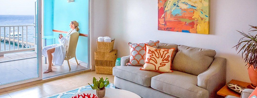 A woman doing yoga near the ocean. Brightly colored room with a sofa.