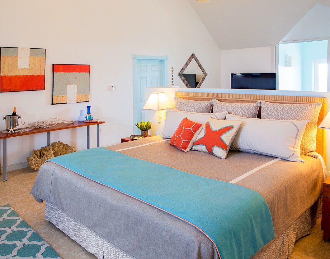Bedroom with king-sized bed, teal accents, abstract art, and blue door.