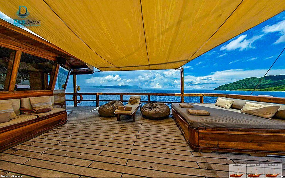 Wooden deck of a boat with seating, ocean view, and yellow canopy.